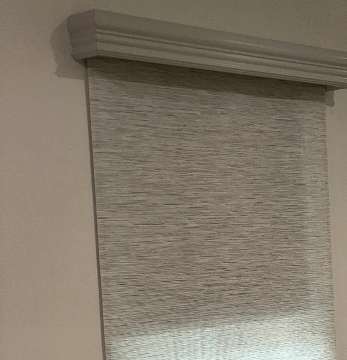 A painted wood cornice header built in our workroom, over a woven roller shade.